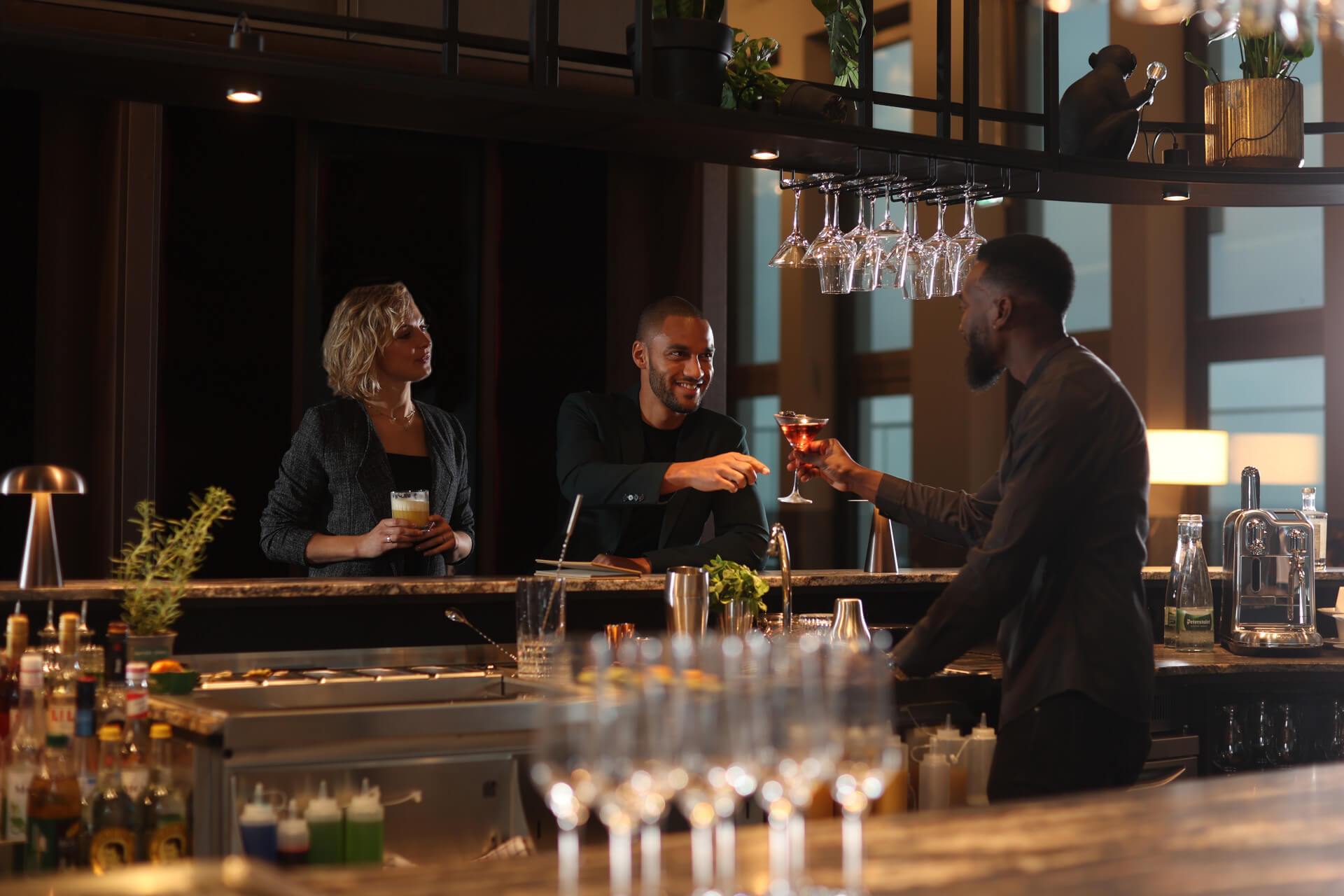 A woman and a man stand at the 15high bar and are being served