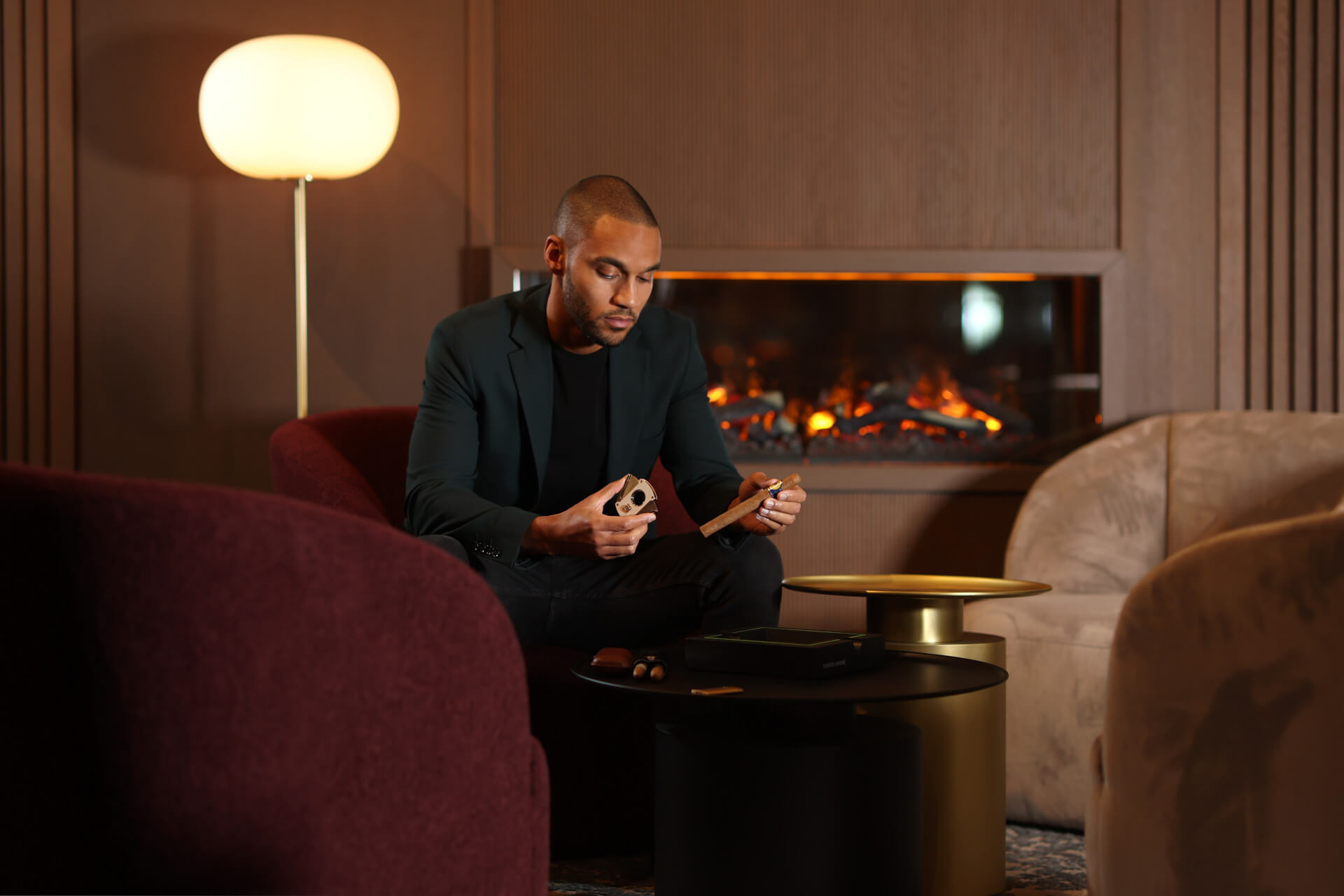 A man sitting in the 15high smokers lounge cutting a cigar