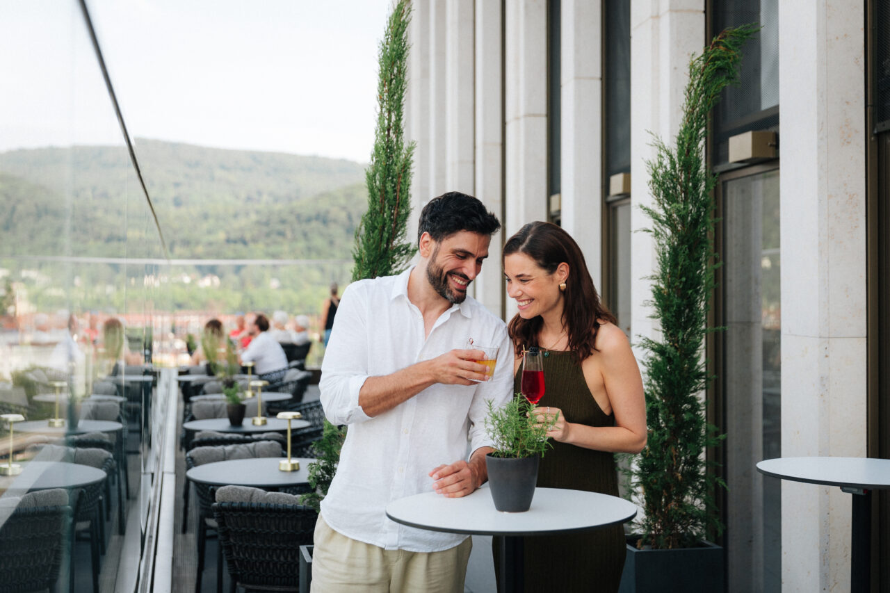Pärchen stößt mit einem Drink auf einer Dachterrasse an